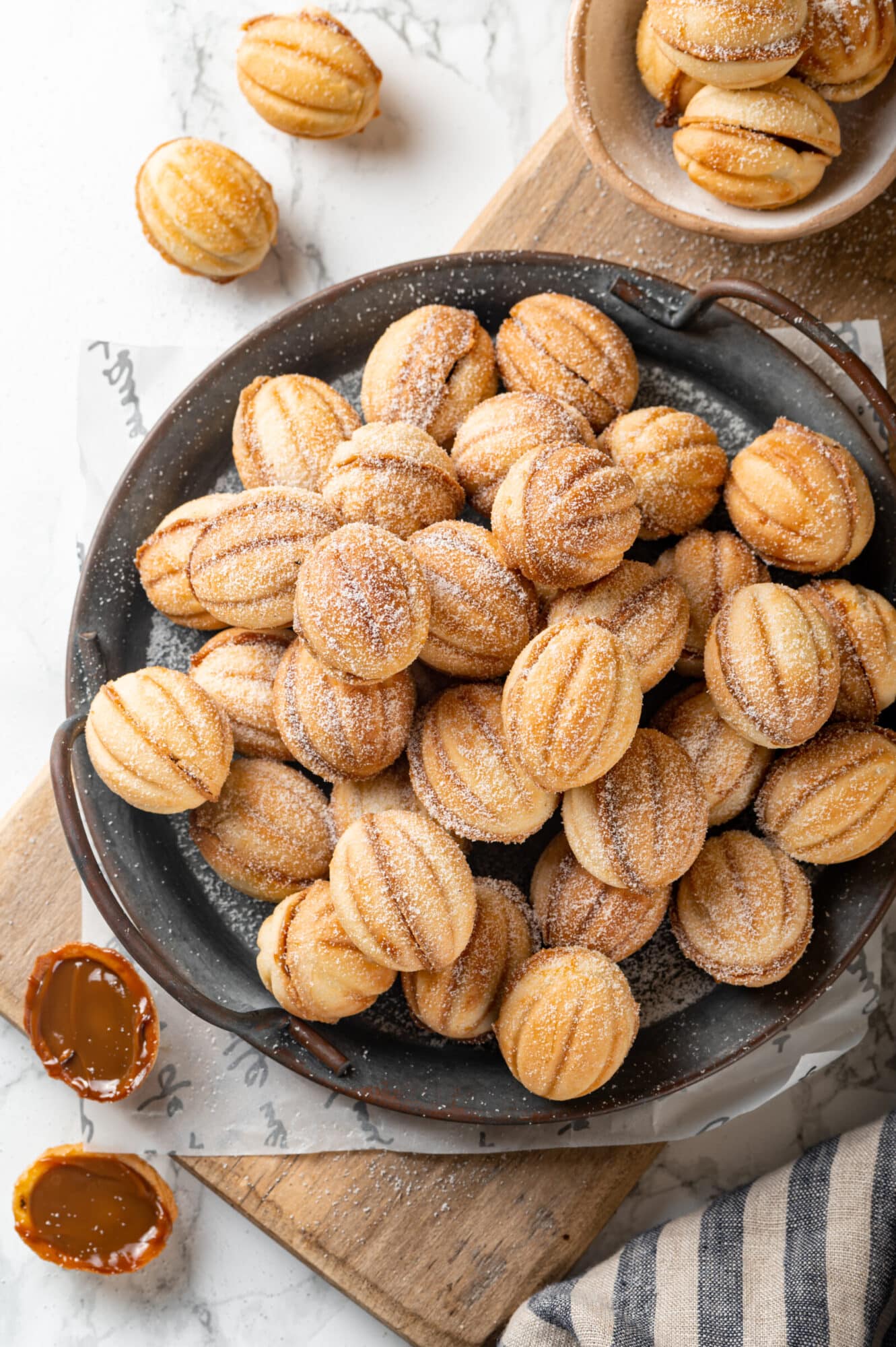 Top view of walnut cookies on a grey plate atop a wooden board.