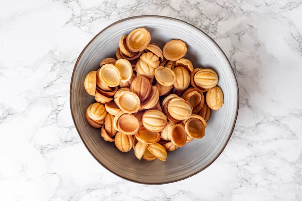 Walnut cookie shells set aside in a bowl.