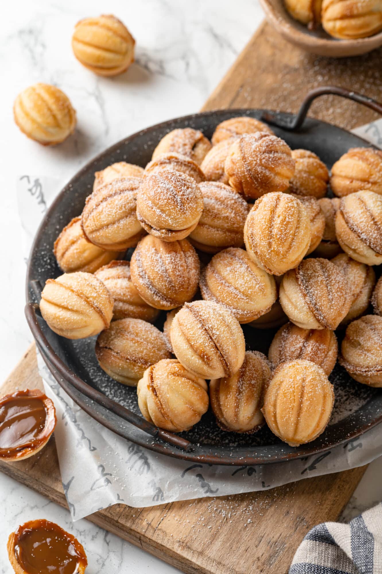 Walnut cookies stack on a plate with handles.