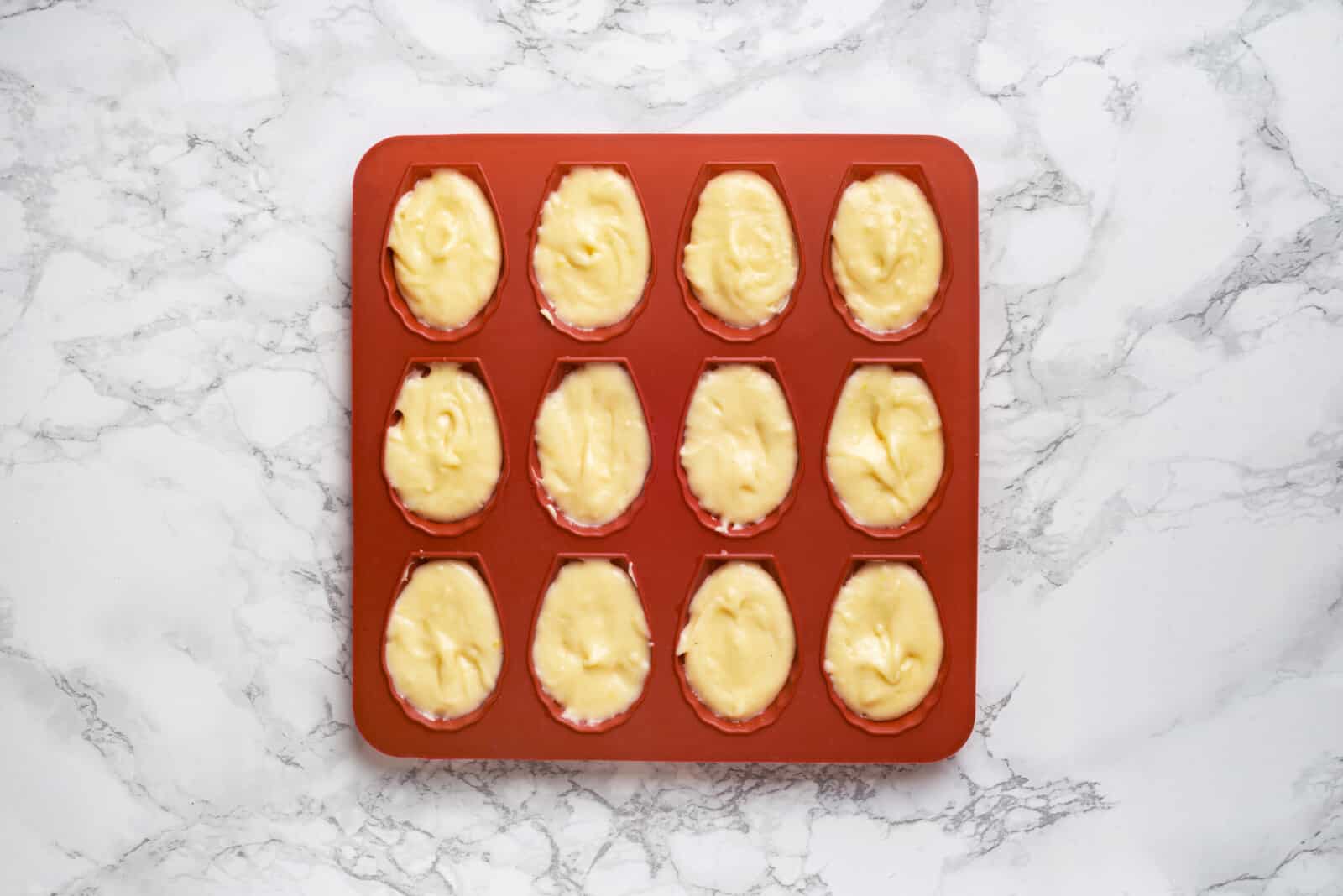 Batter in an orange madeleine pan.