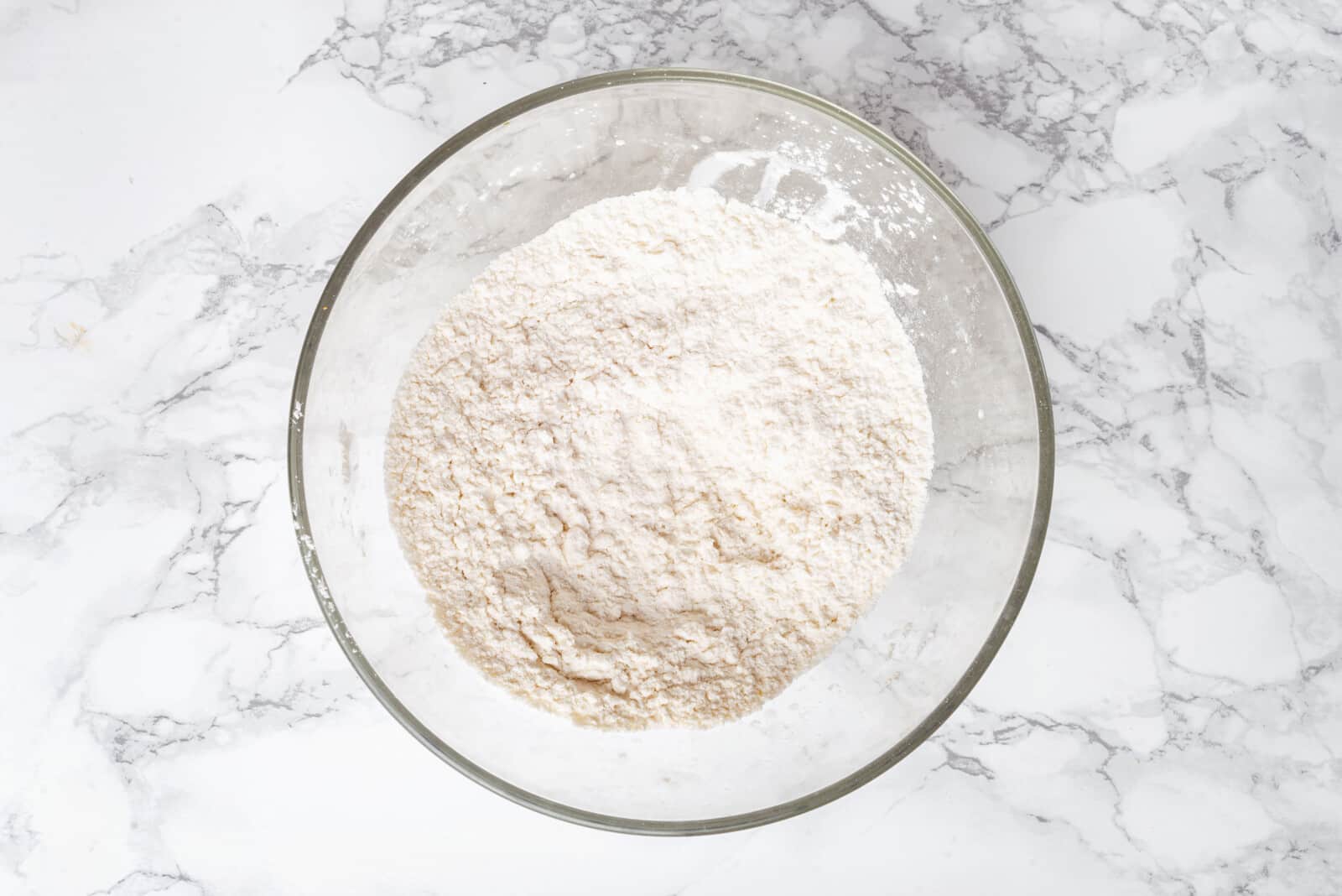 Dry ingredients with flour in a glass bowl.