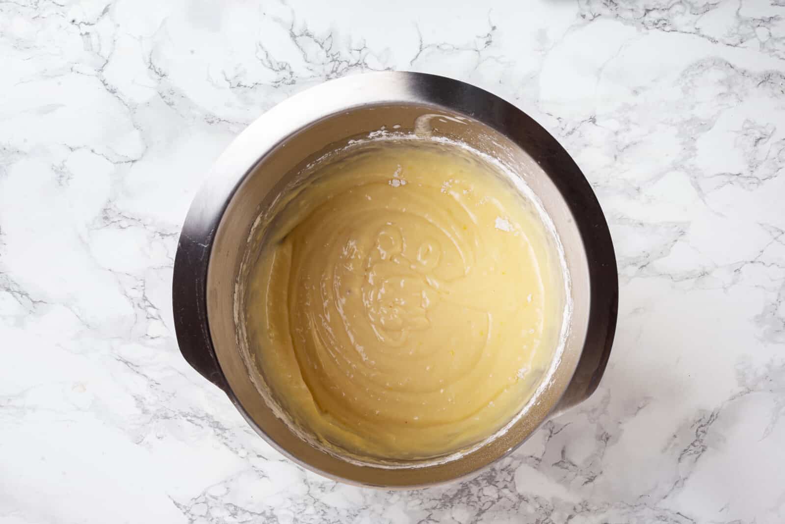 Madeleine cookie batter in a silver bowl.