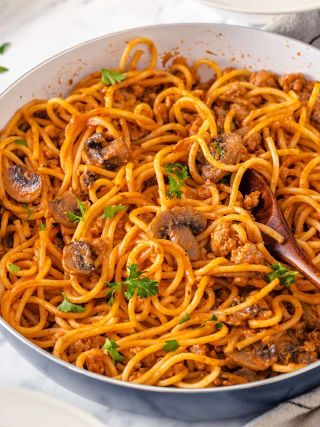 beef spaghetti in a skillet with a spoon.