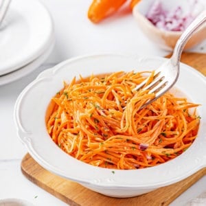 carrot-salad-in-a-white-bowl-on-a-wooden-board-with-a-fork