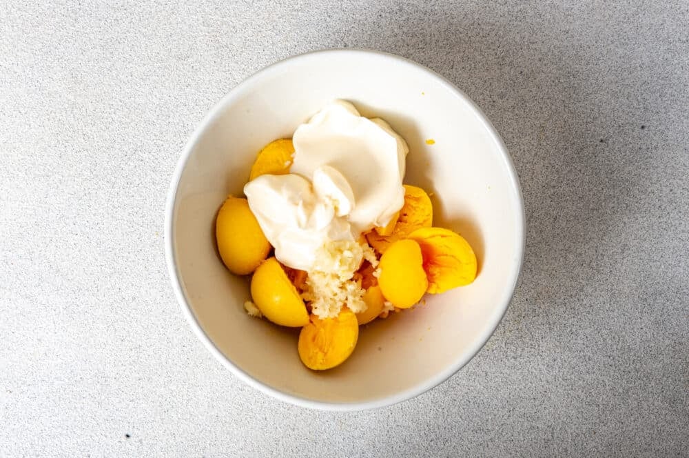 Boiled egg yolks, mayonnaise, and garlic in a white bowl.