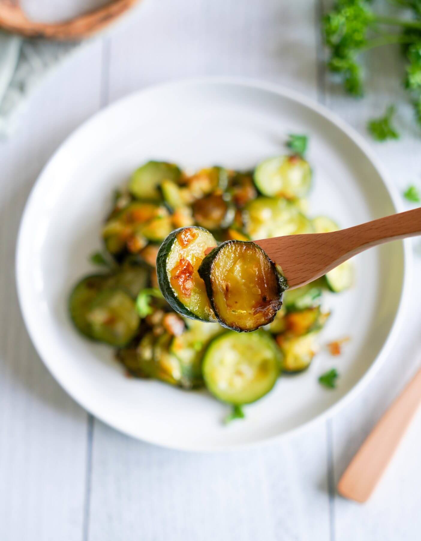 sauteed-zucchini-with-onion-on-a-fork-with-a-plate-of-more-zucchini-in-the-background