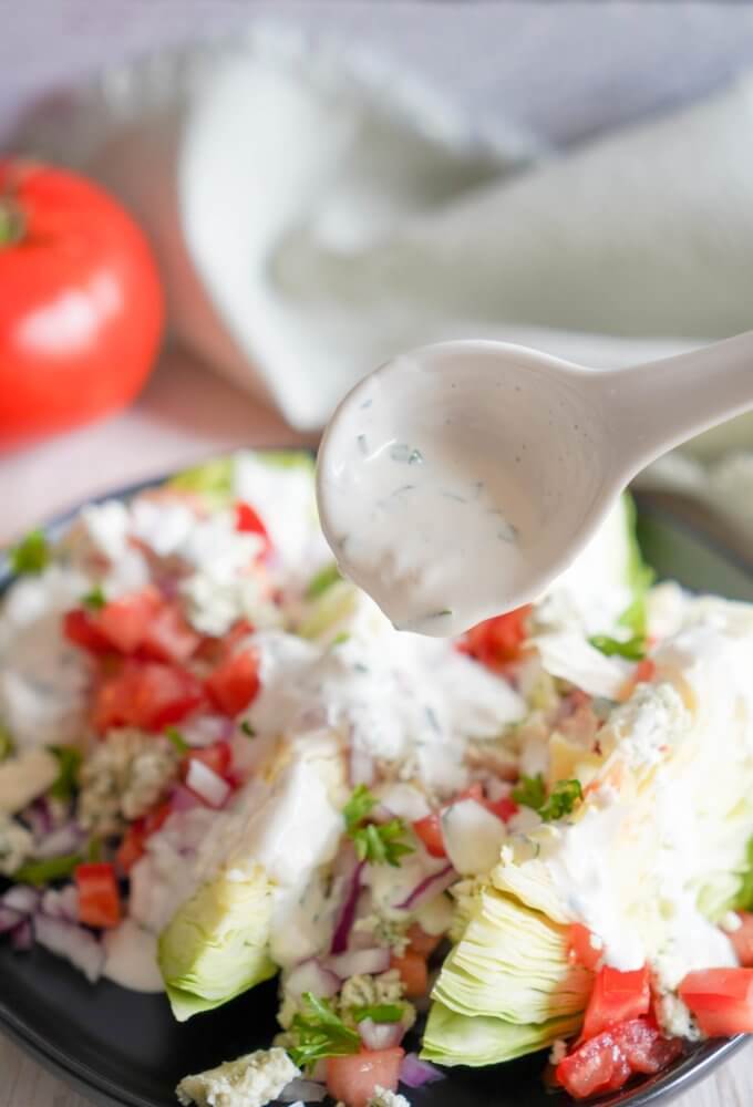 wedge-salad-on-a-black-plate-with-a-spoon-drizzling-ranch-dressing