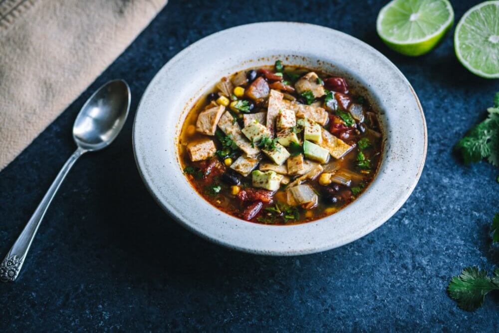 chicken-soup-in-a-bowl-with-a-spoon-and-limes