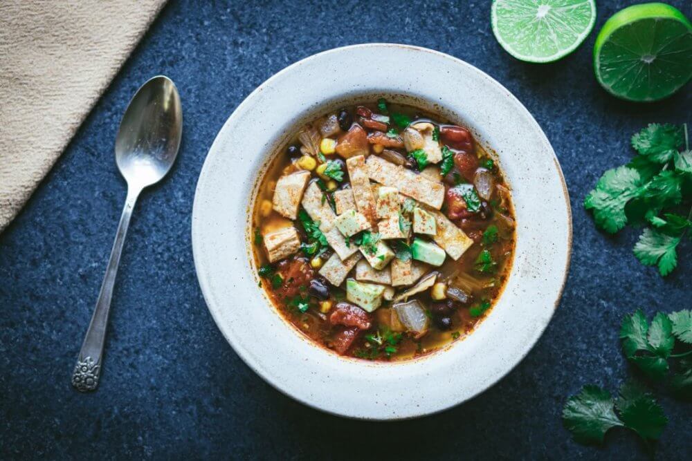 chicken-soup-in-a-white-bowl-with-a-spoon-lime-and-cilantro-on-the-side