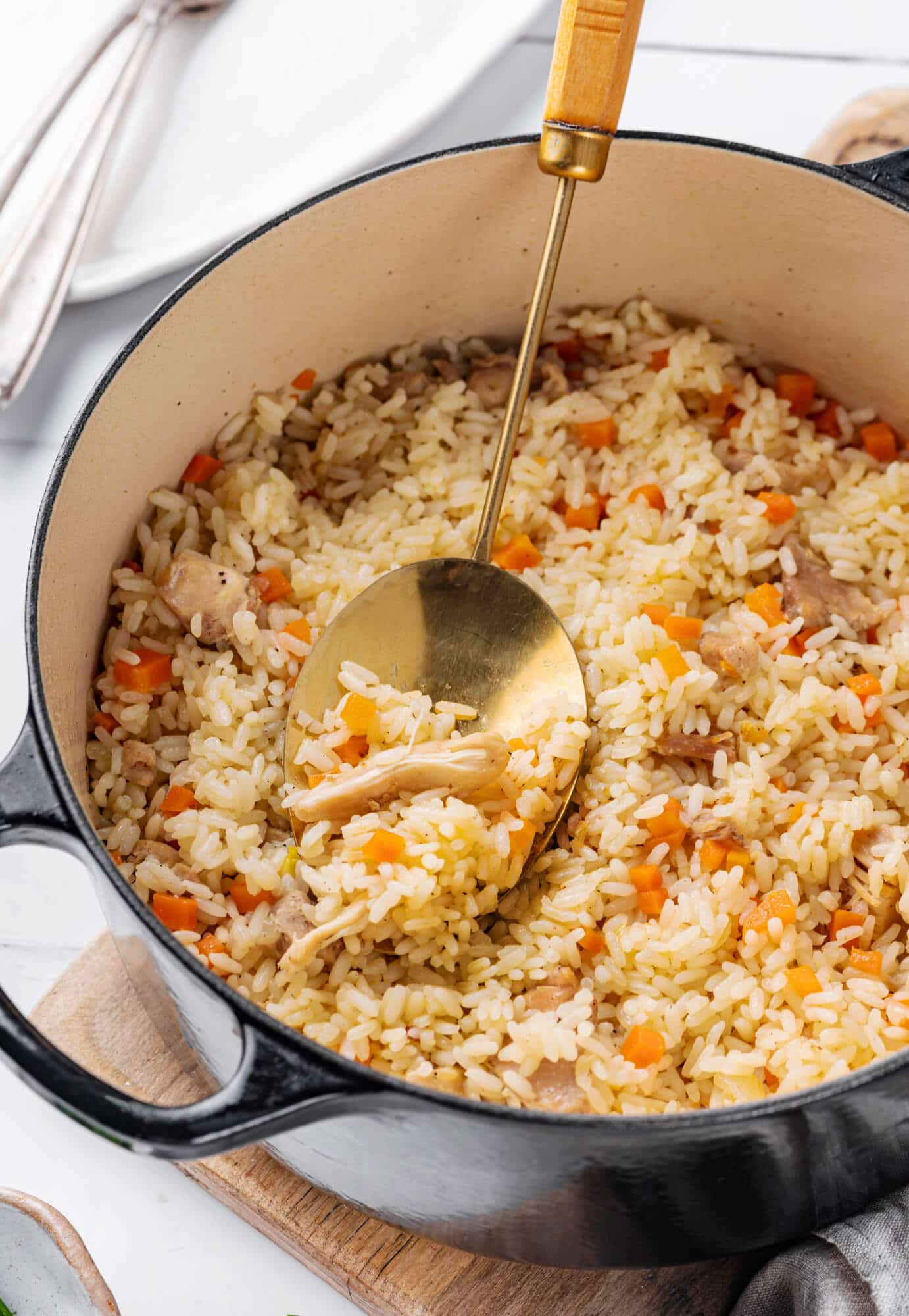 Rice pilaf in a pot with a spoon on a wooden board.