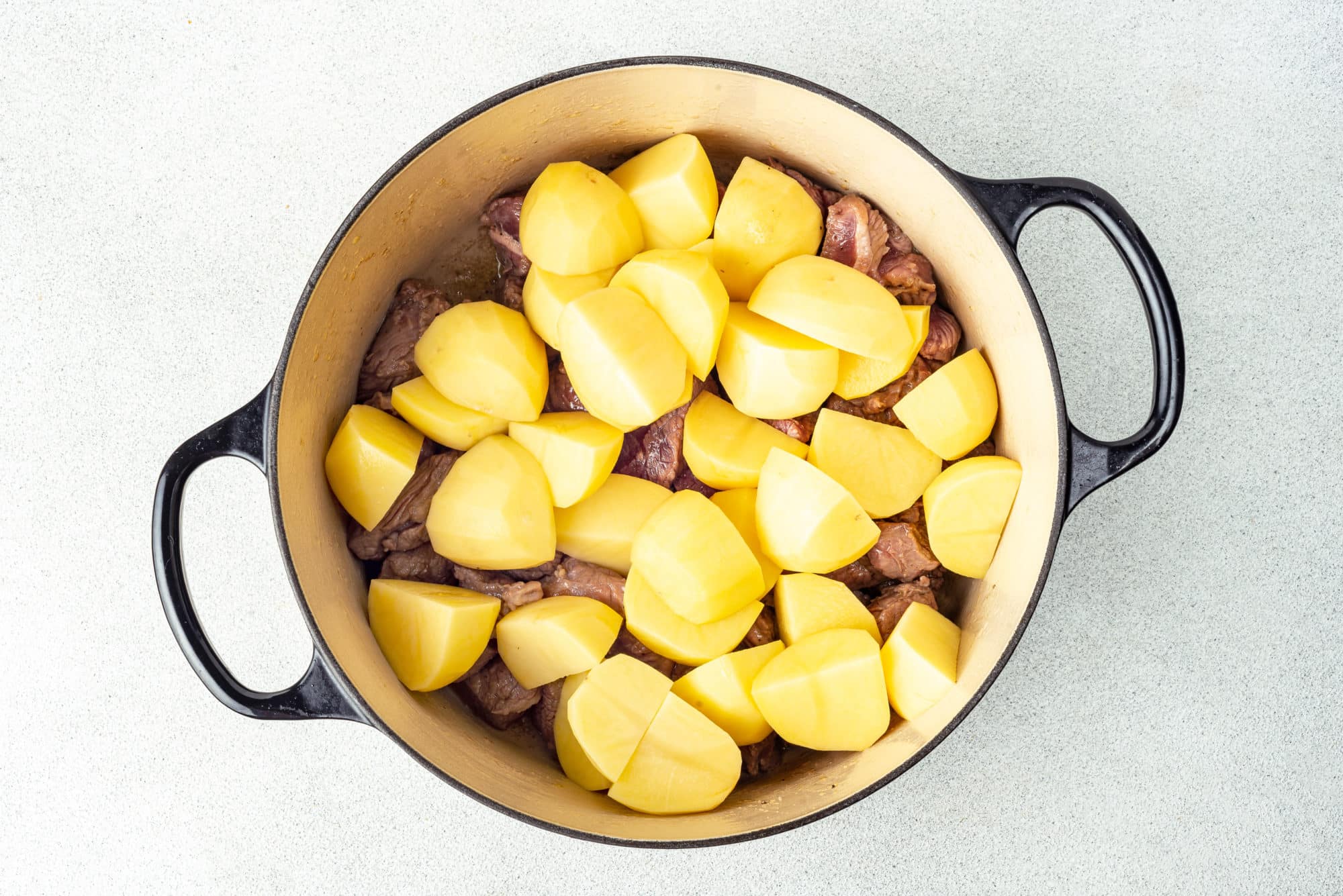 sauteed beef with chopped potatoes in a pot.