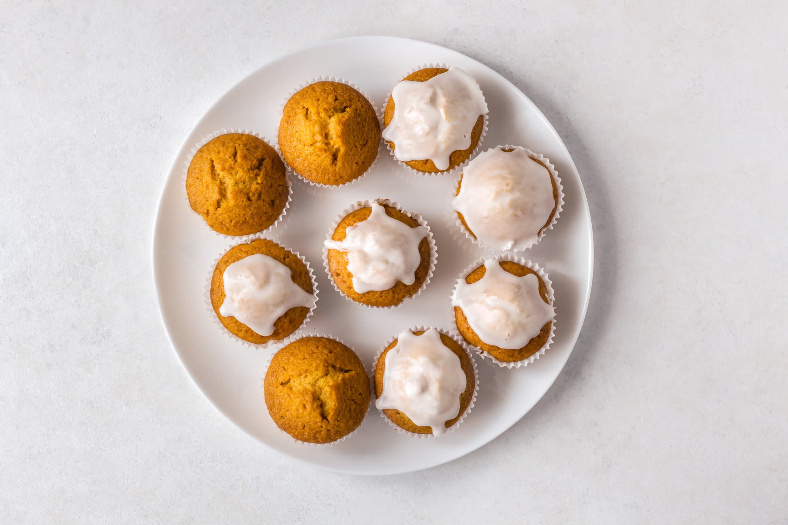 pumpkin muffins, some glazed, on a white plate