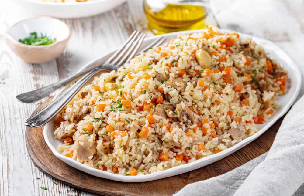 chicken and rice recipe of pilaf on a white plate piled high with two forks.