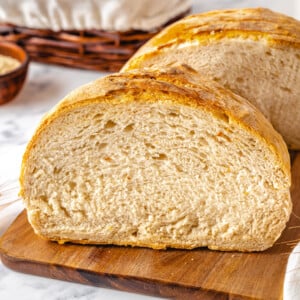 baked loaf cut in half on a wooden board.