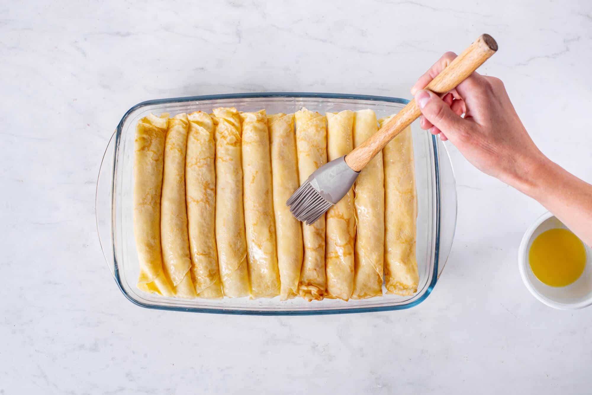 filled-sweet-crepes-in-a-glass-baking-dish-with-a-baster-and-melted-butter