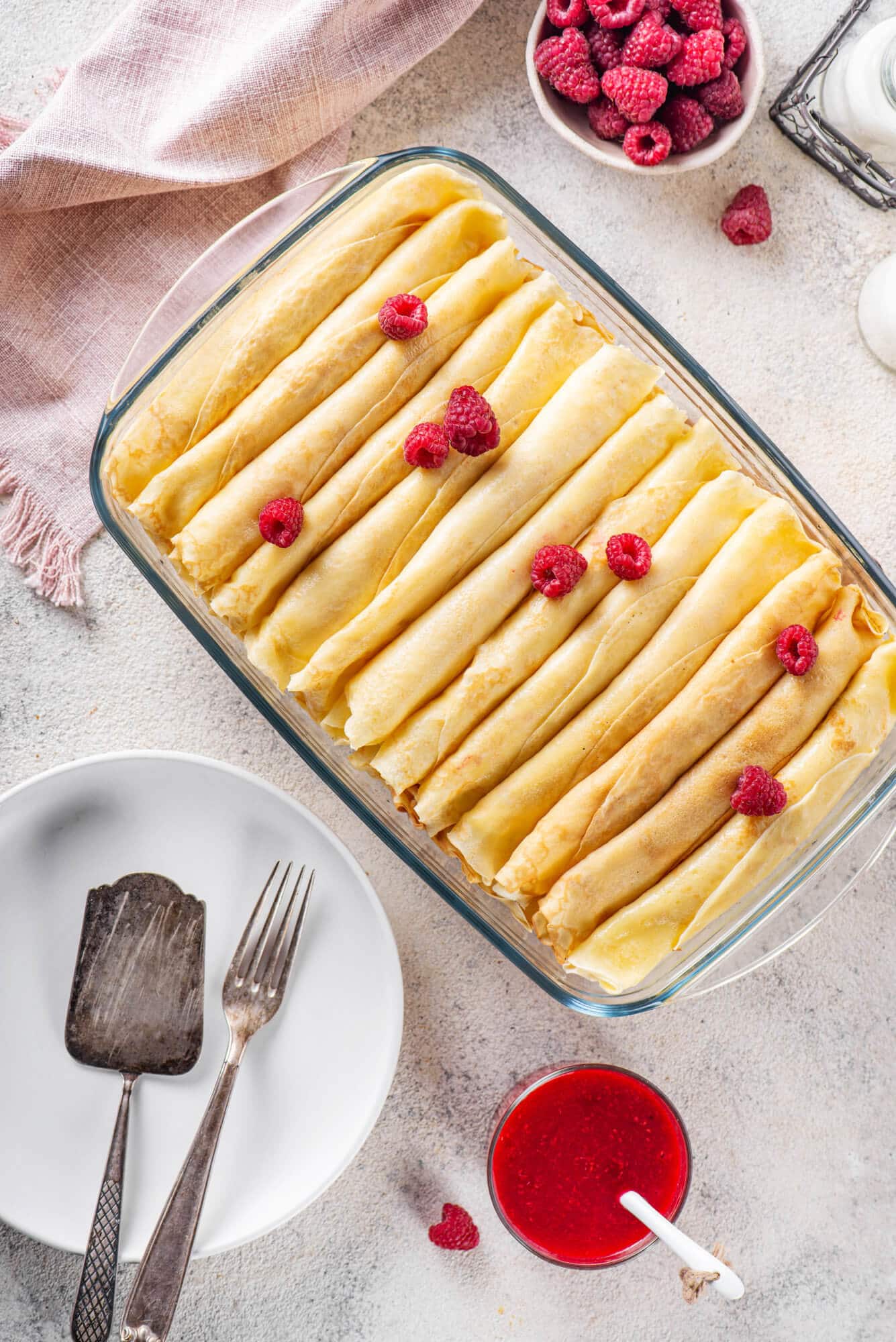filled-sweet-crepes-in-a-glass-baking-dish-with-raspberries-on-top