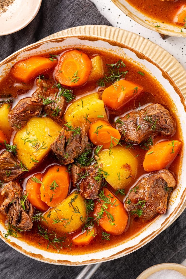 stew in a bowl on a plate on a dark grey towel.