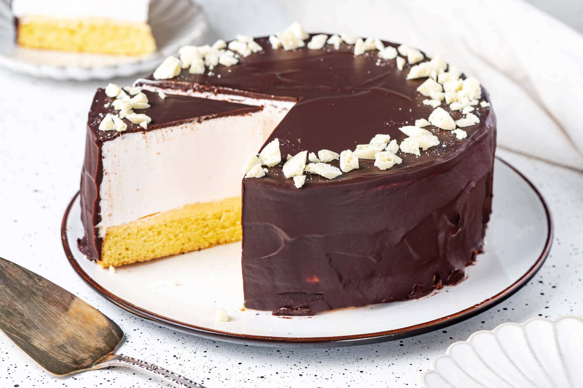 a birds milk cake on a plate with several slices removed to show inside layers.