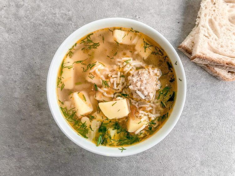 chicken-meatball-soup-in-a-clear-bowl-with-bread-slices-on-the-side