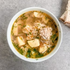 chicken-meatball-soup-in-a-white-bowl-with-bread-slices-on-the-side