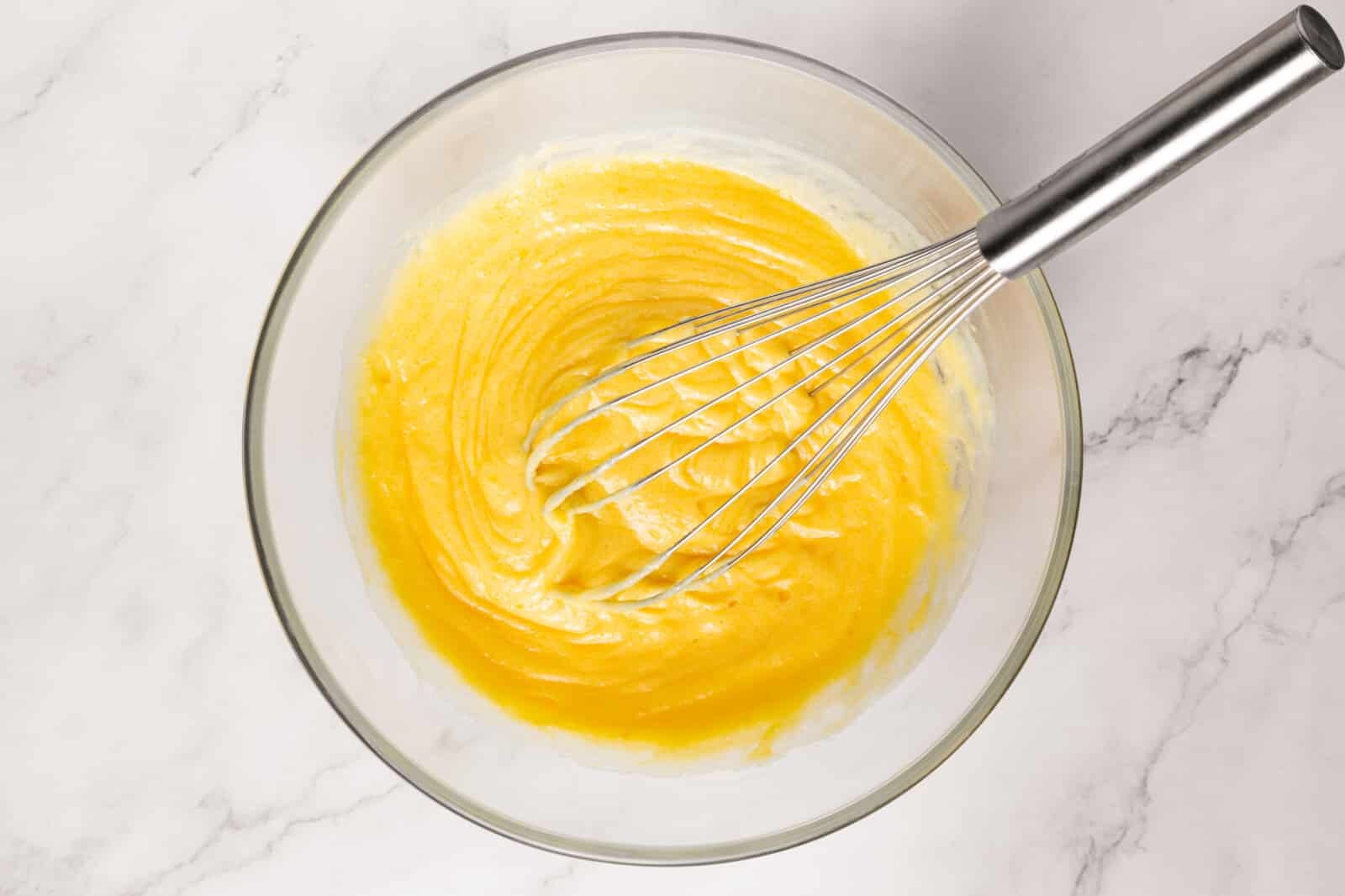 Meringue Jam Filled Tartlets Batter in a glass bowl with a whisk.