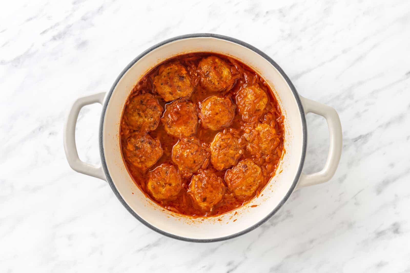 Cooked meatballs in a pot with tomato sauce.