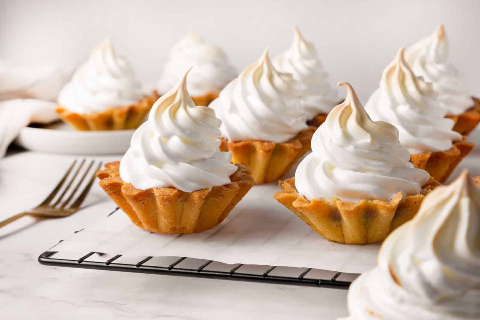 Meringue Jam Filled Tartlets Ready to serve meringue tartlets atop a wire rack.