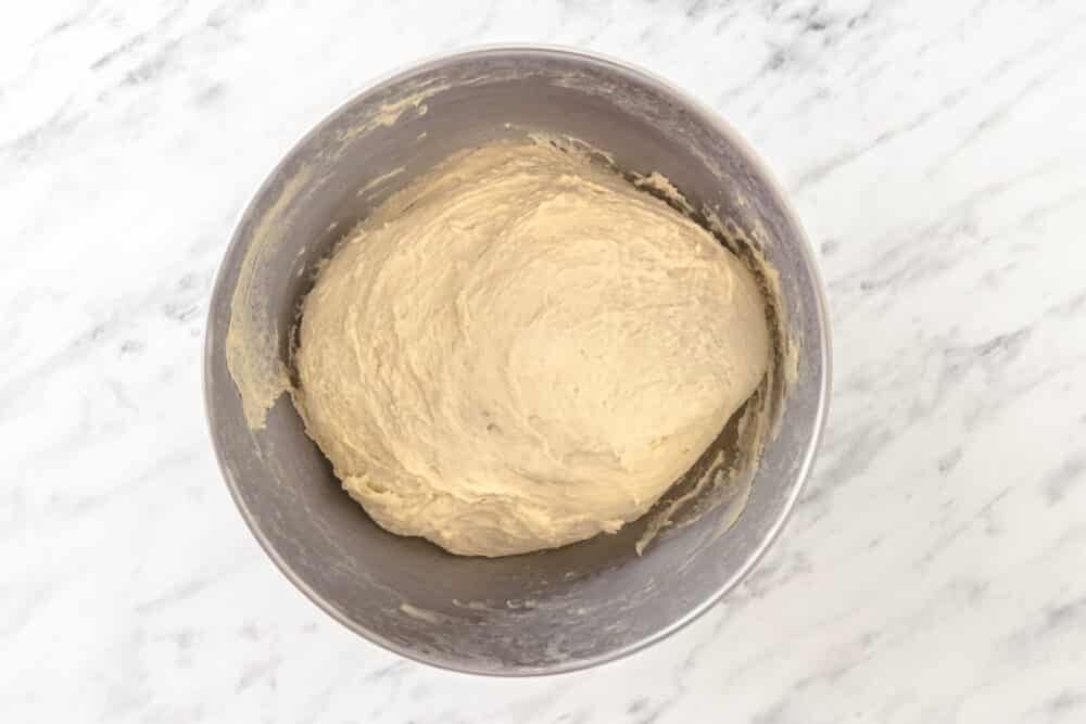 Roughly shaped dough in a silver mixer bowl.