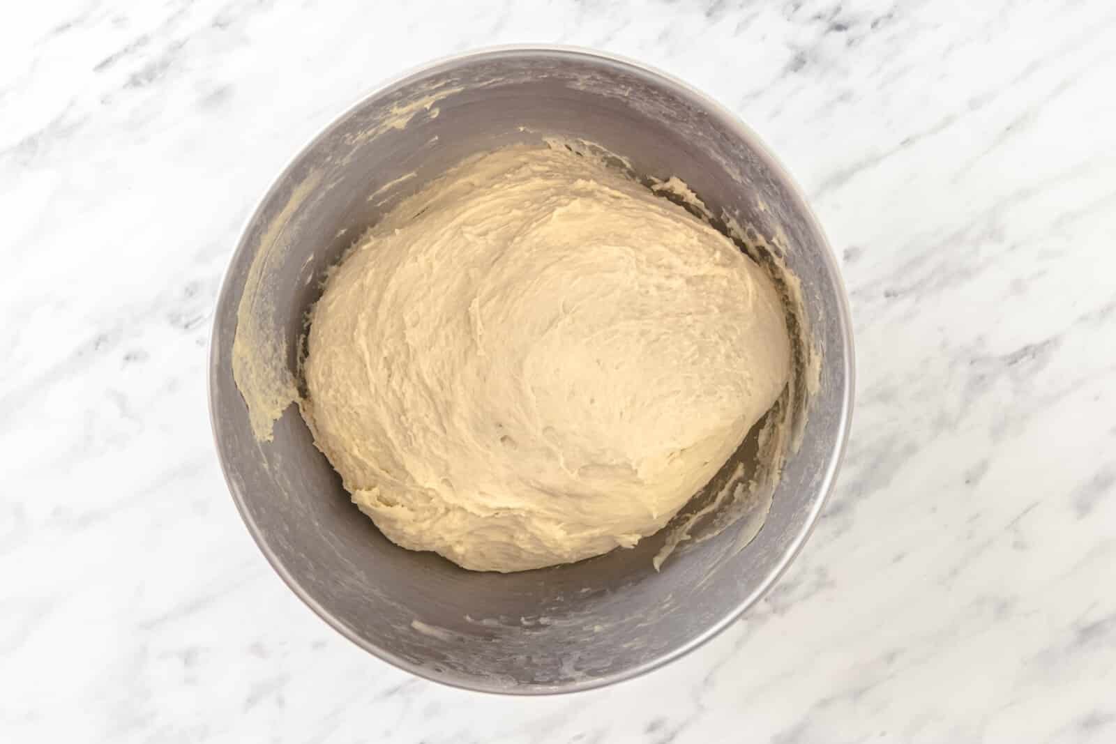 Roughly shaped dough in a silver mixer bowl.