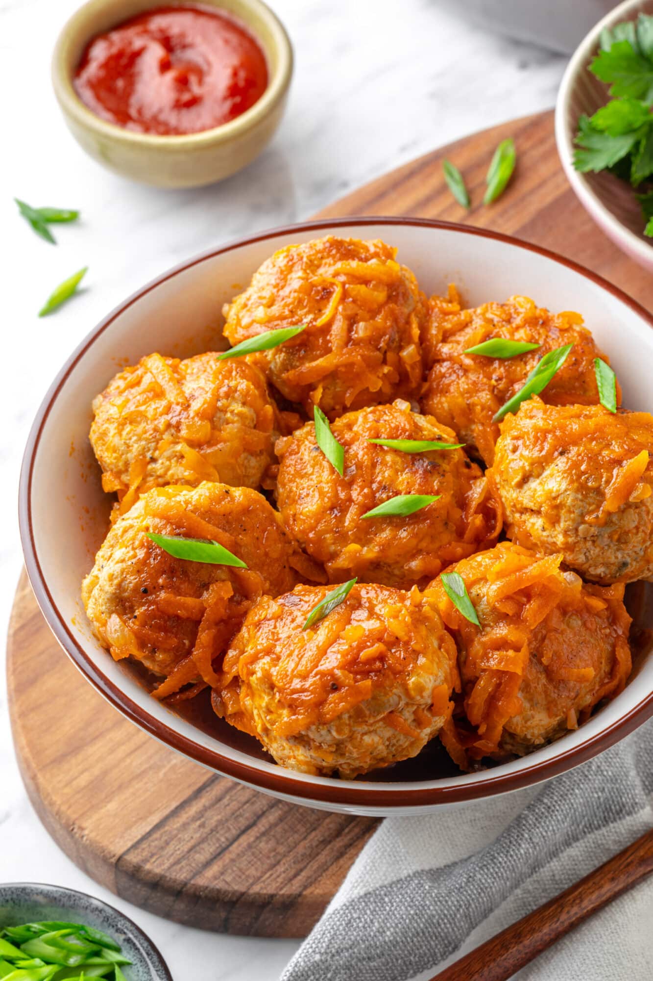 Serving meatballs with tomato sauce in a bowl with chopped green onion garnish.