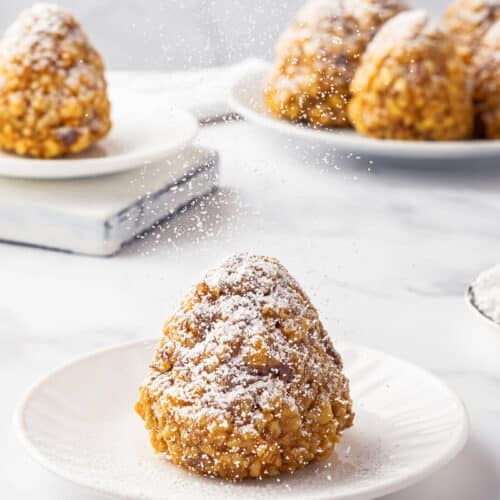 Sweet winter trees on a white plate being dusted with powdered sugar.