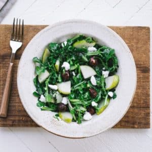 arugula-pear-salad-in-a-white-bowl-on-a-wooden-board-with-a-fork