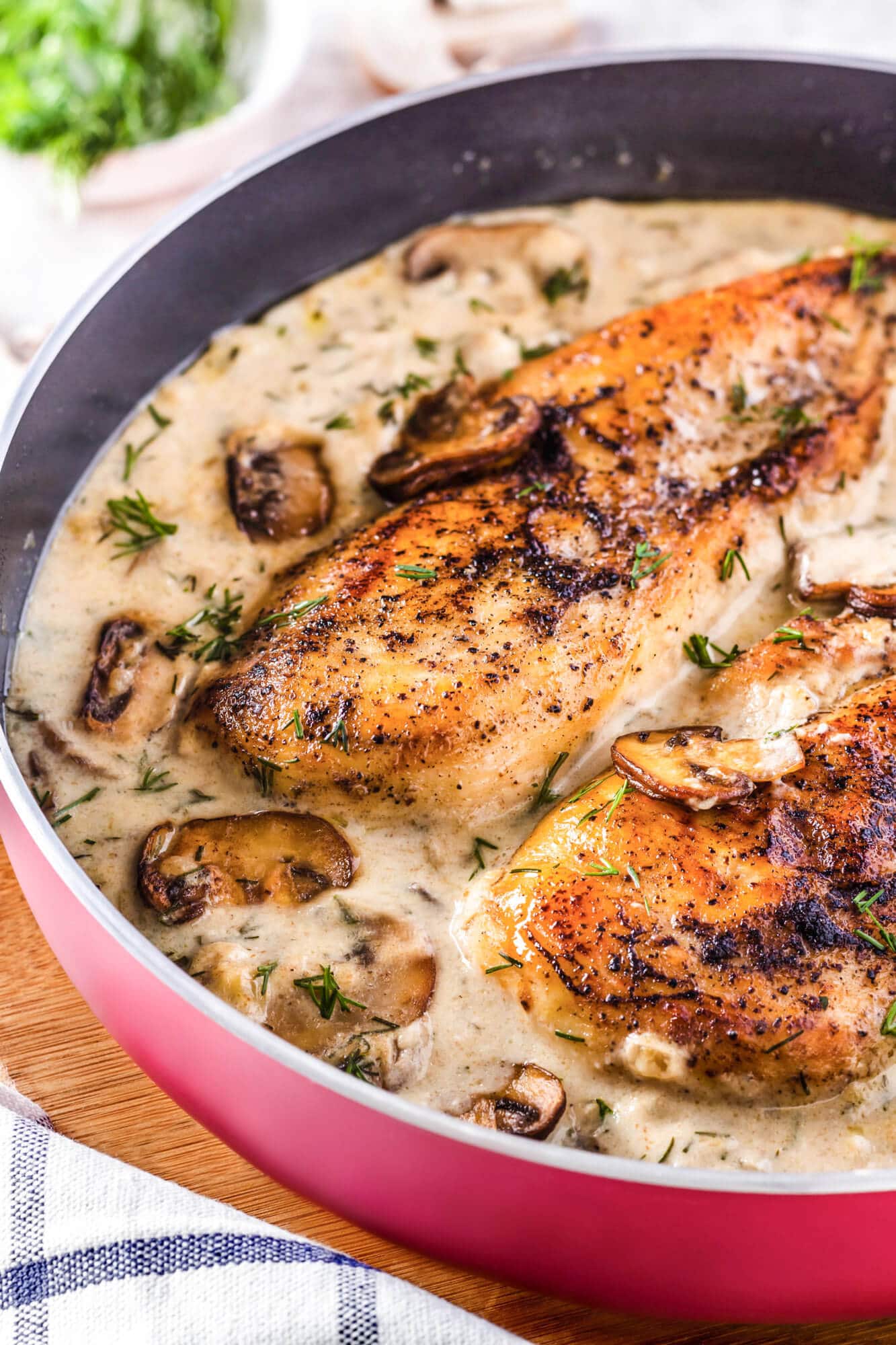 cooked-chicken-breast-in-a-red-pan-on-a-cutting-board-with-creamy-mushroom-sauce-fresh-dill