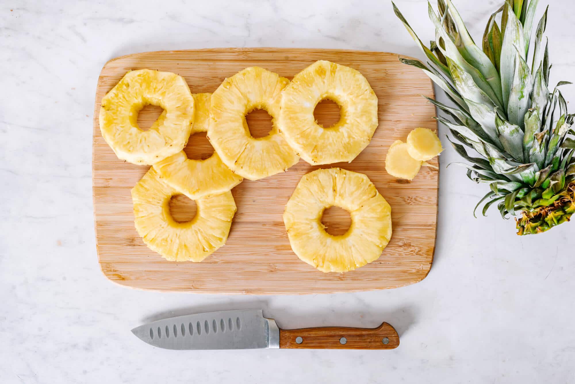 pineapple-chopped-on-a-wooden-board-with-a-knife-and-a-pineapple-crown-on-the-side