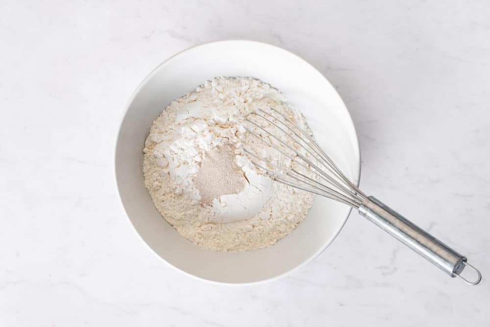 flour-and-yeast-in-a-white-bowl-with-a-whisk