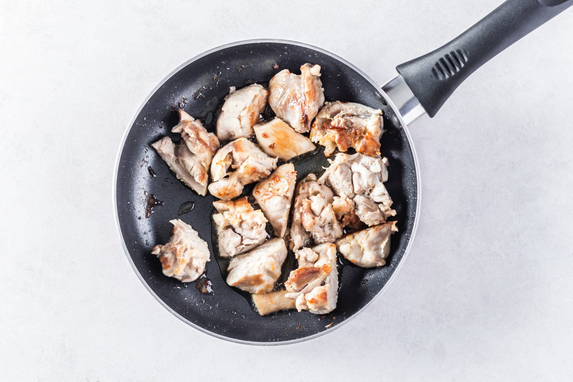 Chicken browning in a skillet while sautéing.
