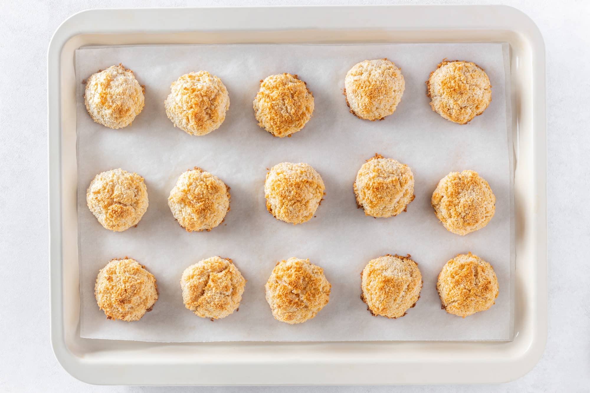 Coconut macaroons baked on parchment paper and a baking tray.