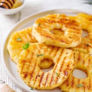 pineapple-slices-on-a-white-plate-with-a-bowl-of-honey-with-a-honey-dipper