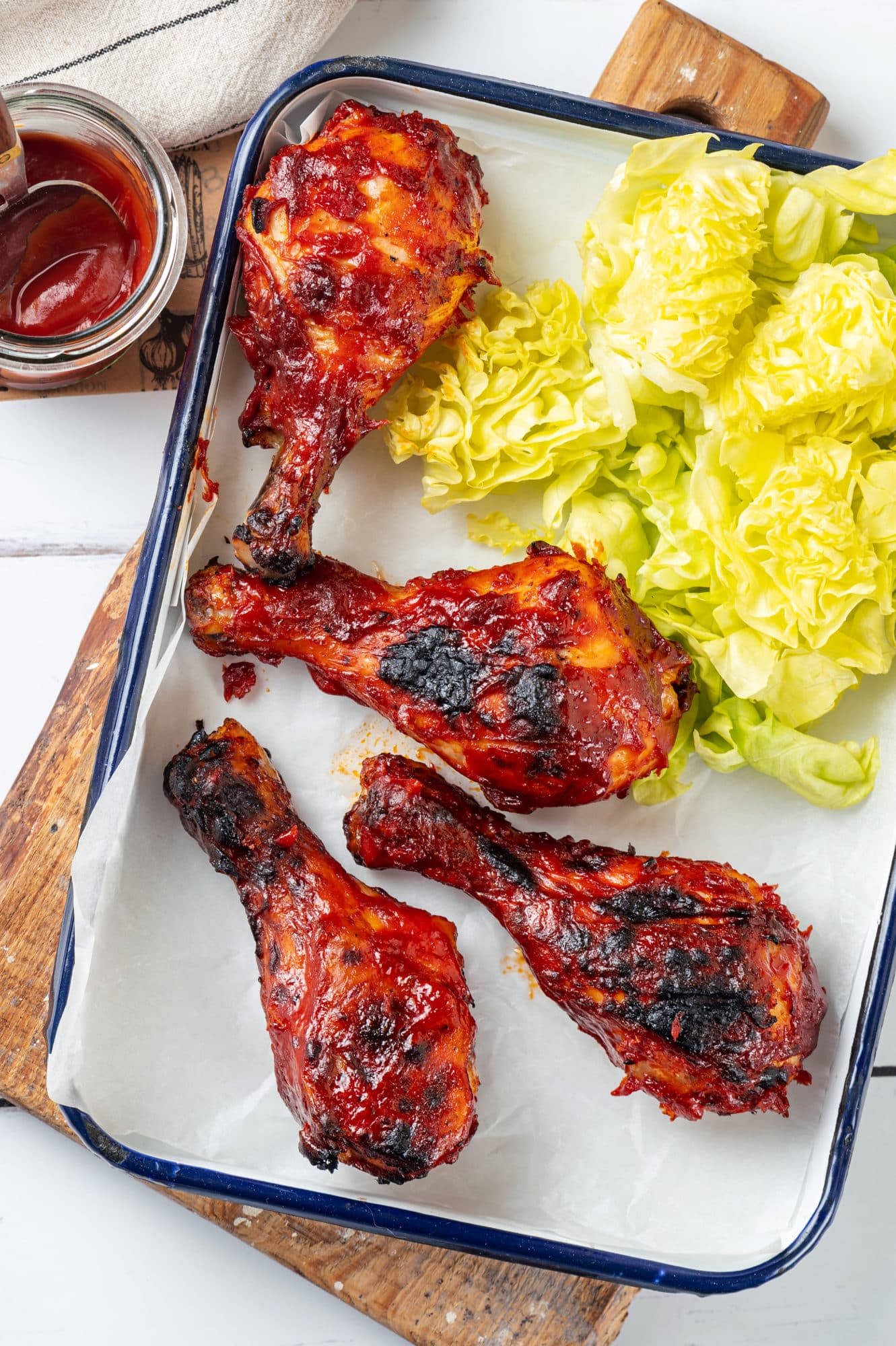 chicken-drumsticks-on-a-baking-tray-on-a-cutting-board-with-lettuce