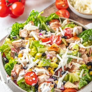 mexican salad with shredded cheese on top in a grey bowl.