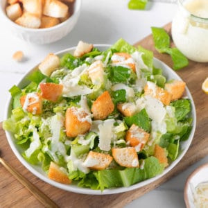 caesar-dressing-in-a-white-bowl-with-a-fork-on-a-wooden-board