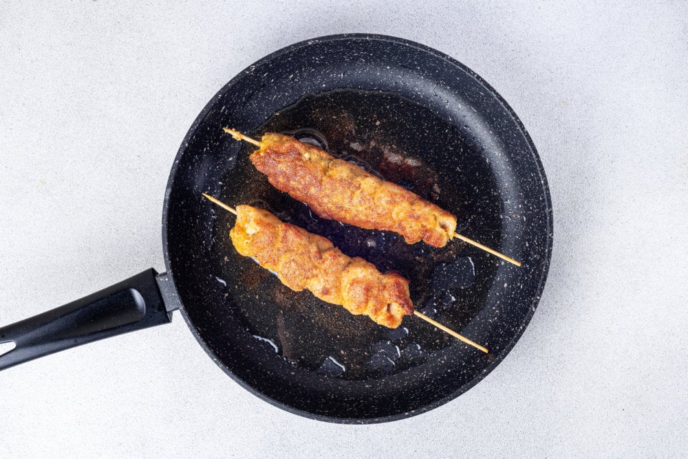 black pan with two chicken skewers
