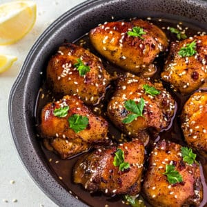 a black dish with soy sauce chicken thighs and parsley in soy sauce marinade.