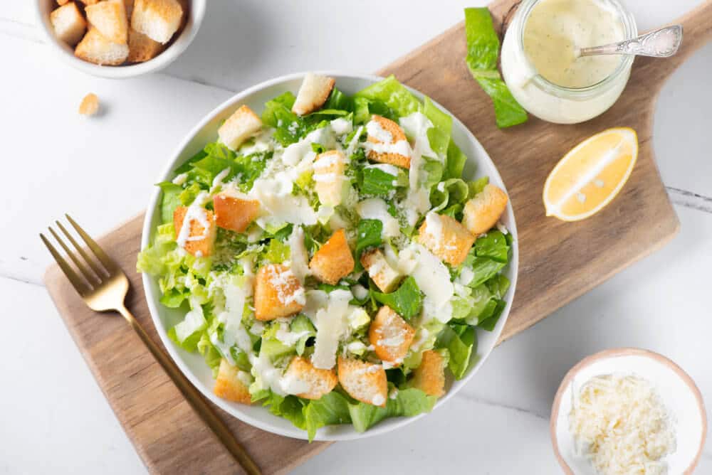 caesar-dressing-in-a-white-bowl-with-a-fork-on-a-wooden-board