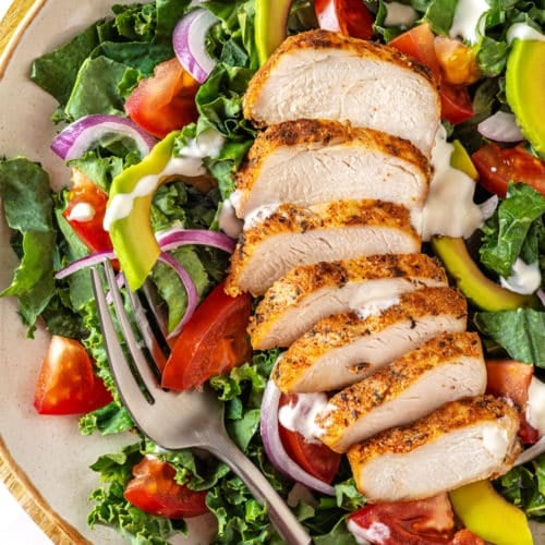 cajun chicken salad on a white plate with a thin brown rim on a wooden board.