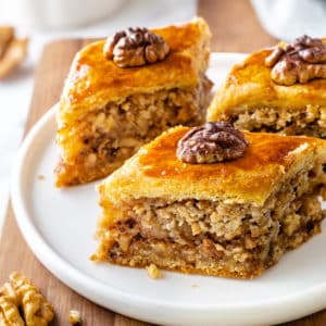 baklava-pieces-on-a-white-plate-on-a-wooden-board-with-walnut-pieces-on-top