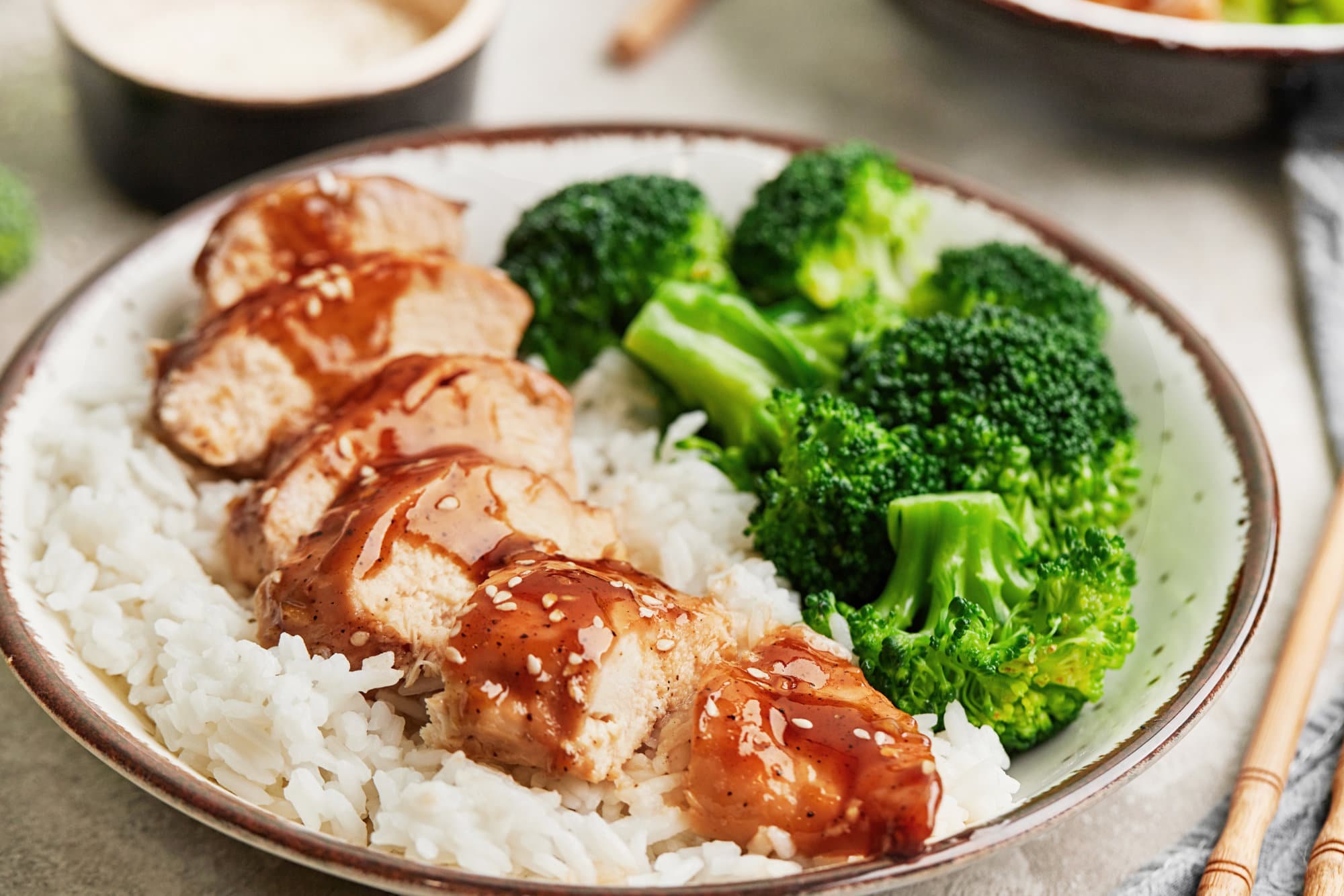 Sliced teriyaki chicken on a bed of rice, with broccoli on the side.