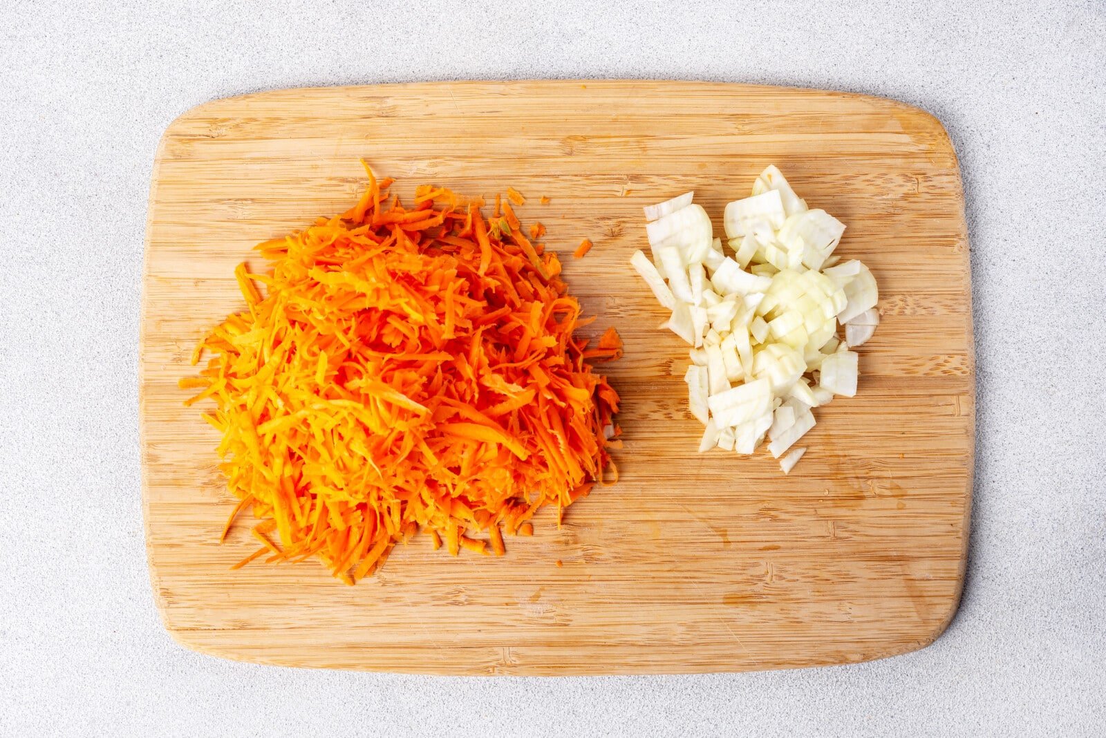 Chopped onion and carrot on a cutting board.