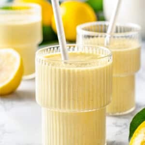 blended lemon smoothie in glasses with straws.