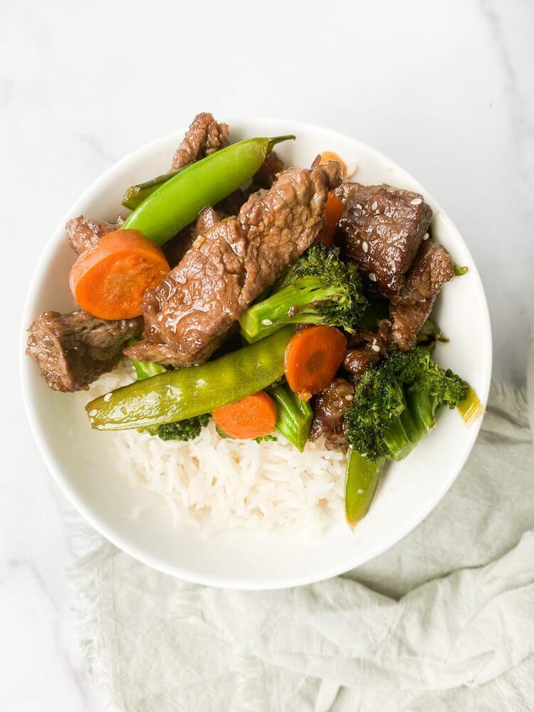 beef-rice-and-veggies-in-a-white-bowl-with-a-towel-on-the-side